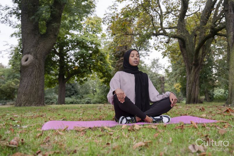 Woman in hijab meditating in park