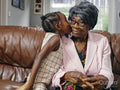 Great granddaughter kissing great grandmother on cheek