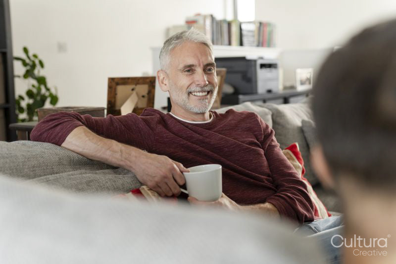 Smiling male couple relaxing on sofa at home
