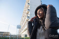 Portrait of smiling woman in black overcoat with hood outdoors