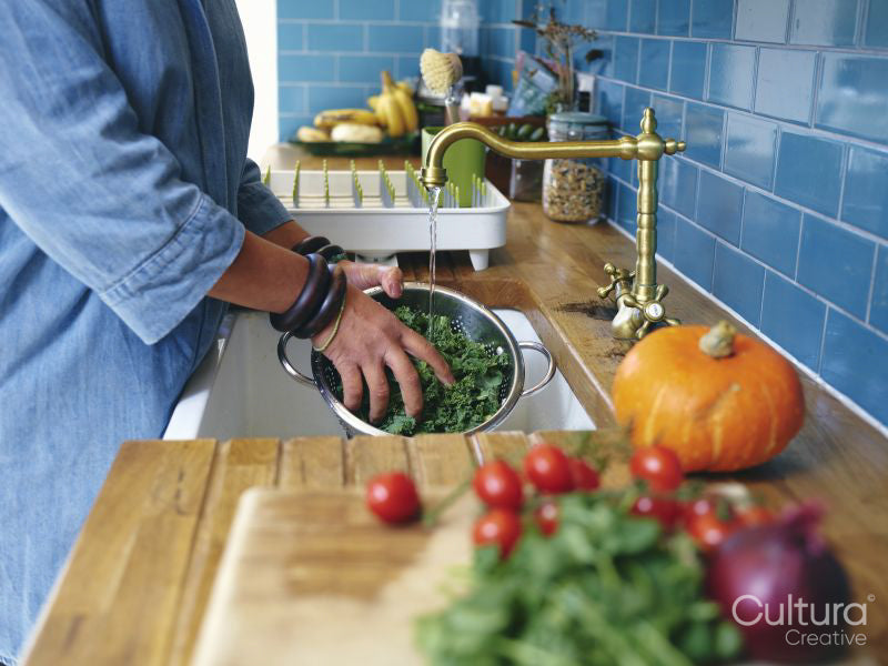 Woman washing vegetables in kitchen sink