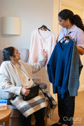 Nurse helping senior lady to choose clothes at nursing home