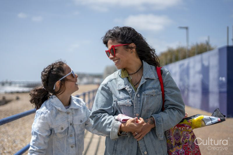 Mother and daughter walking along beach