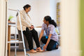 Nurse helping senior lady to put on her shoes at nursing home
