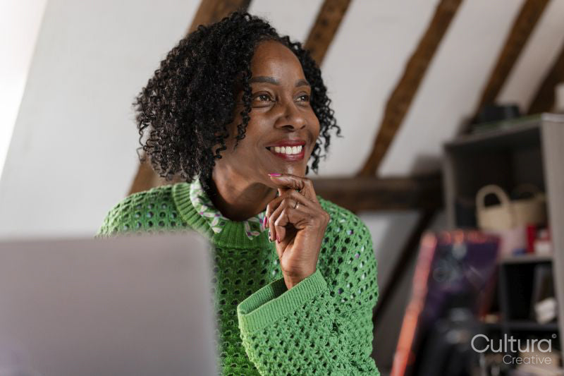 Smiling businesswoman looking away while working on laptop in office