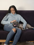 Woman stroking French Bulldog on sofa at home