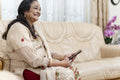 Senior woman using smart phone while sitting on sofa in living room