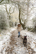 Rear view of woman walking with dog in snow covered forest