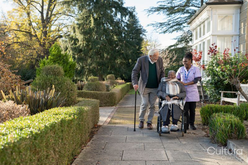 Senior people accompanied by nurse going on walk in park