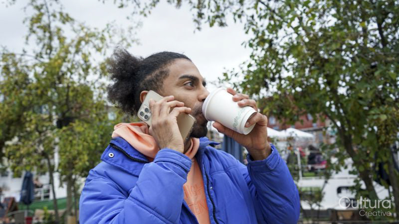 Young man drinking coffee while talking on phone