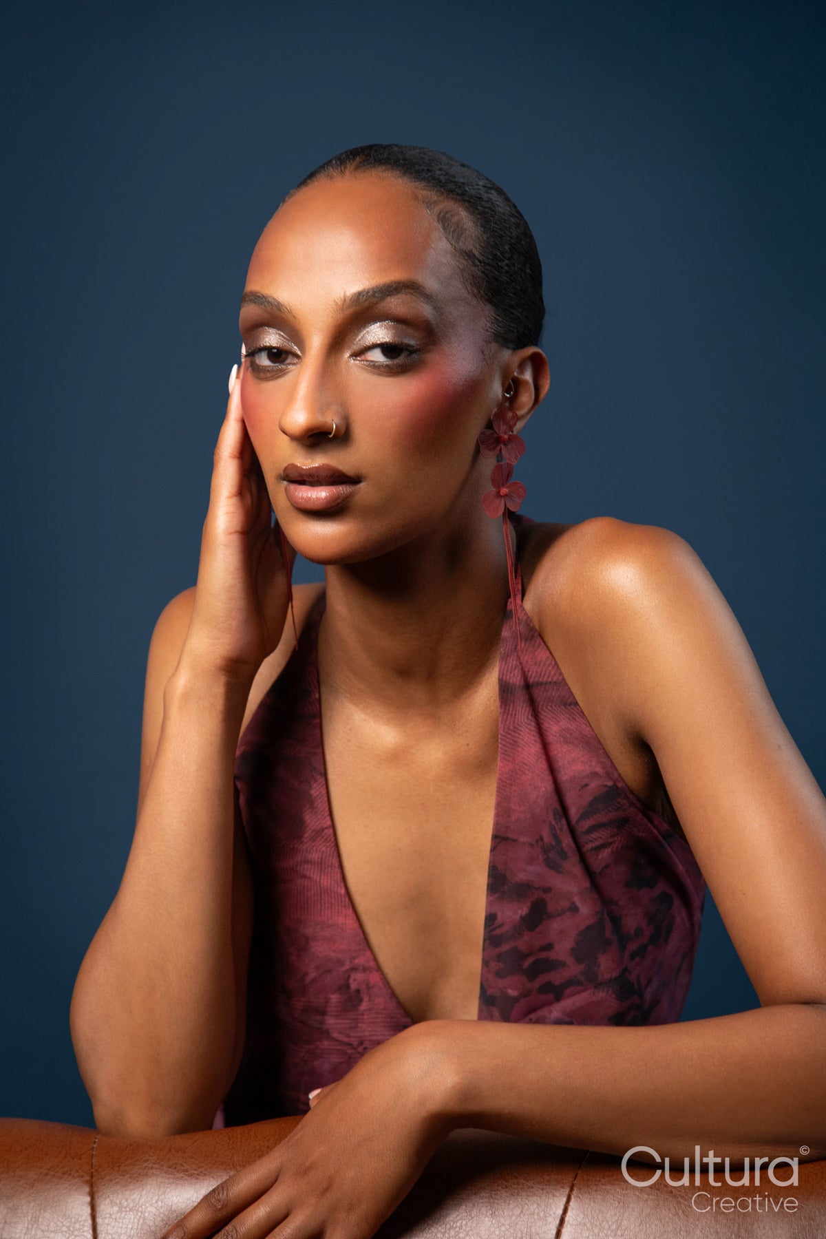 Woman in a burgundy dress with red earrings on a blue background