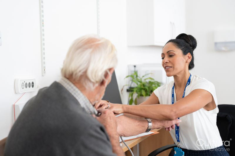Female doctor taking senior patients blood pressure in office