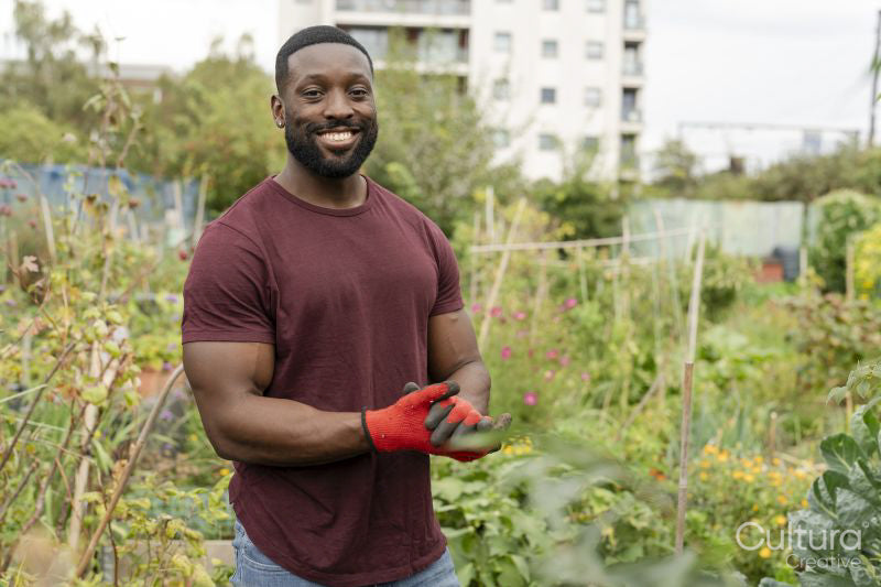 Portrait of smiling man standing in urban vegetable garden