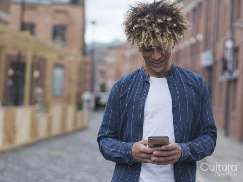 Smiling man using smart phone in city