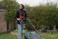 Woman wearing hijab mowing grass in backyard