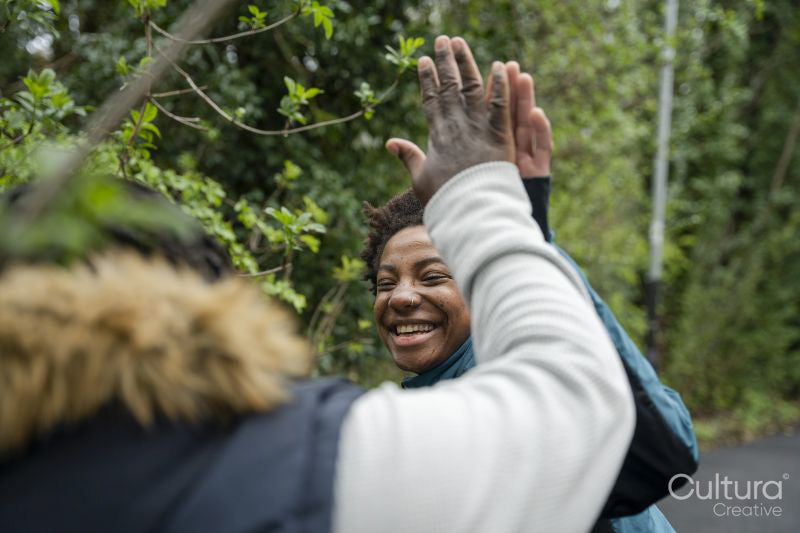 Mother and daughter giving high-five during walk in park