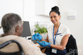 Smiling female doctor talking to senior patient sitting in wheelchair in office