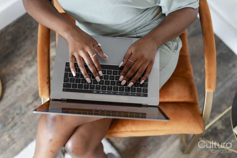 Young woman using laptop while sitting in armchair at home
