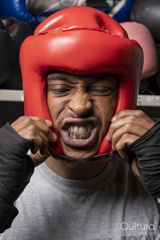 Mature man putting on head protector for boxing match