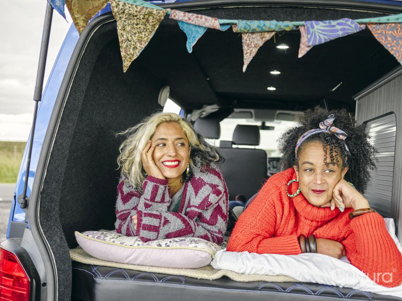 Women lying in back of van and looking at view