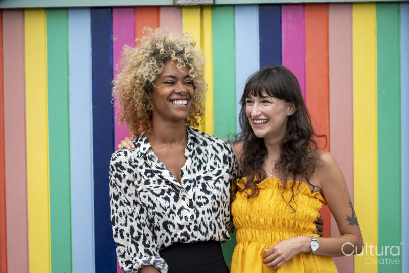 Female couple standing in front of colorful striped wall