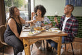 Smiling friends enjoying snacks and red wine at restaurant table