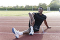 Athlete stretching legs before training at sports track