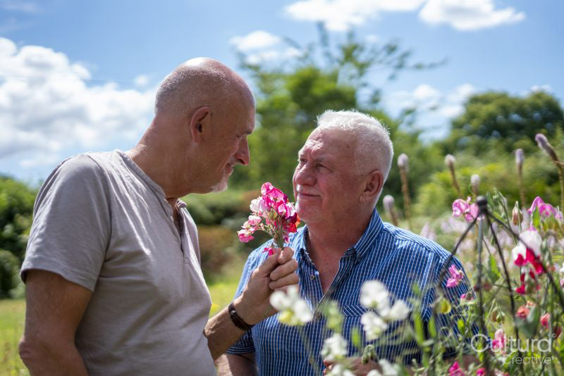 Senior male couple smelling flowers