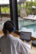 Woman sitting in hotel lounge and using laptop with headphones