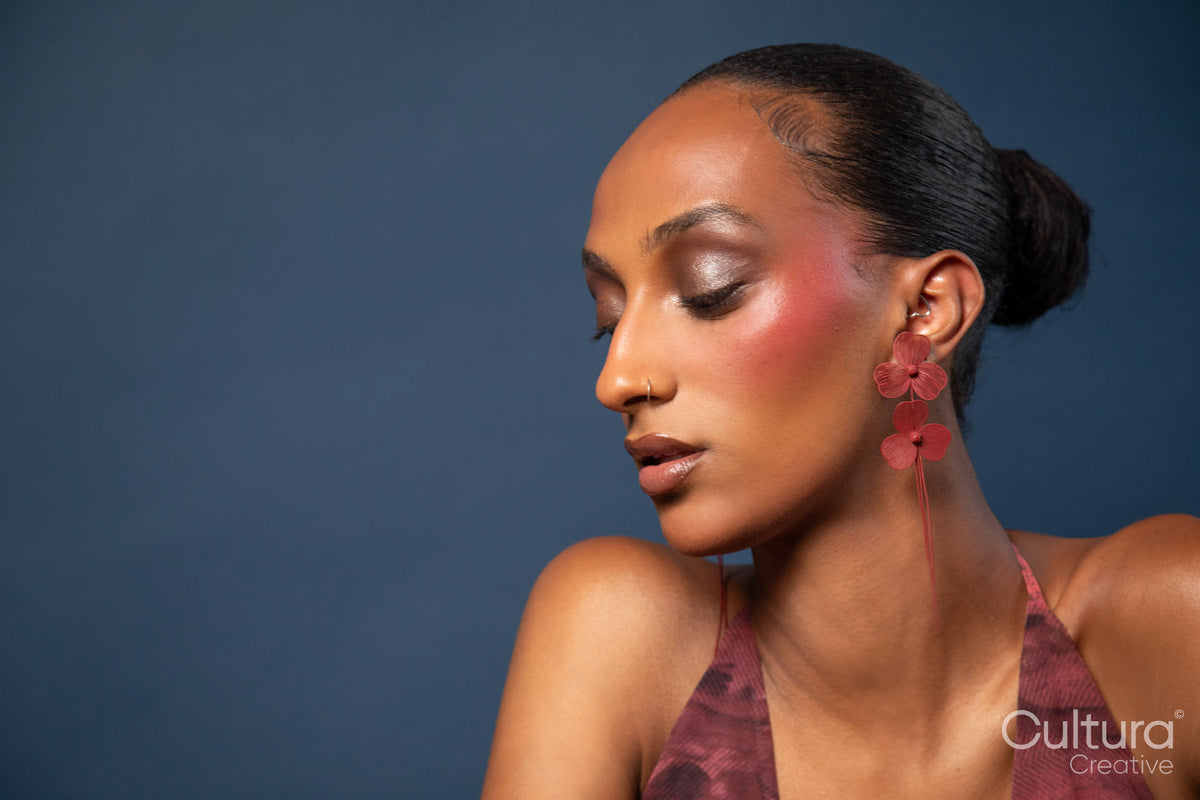 Woman in a burgundy dress with red earrings on a blue background