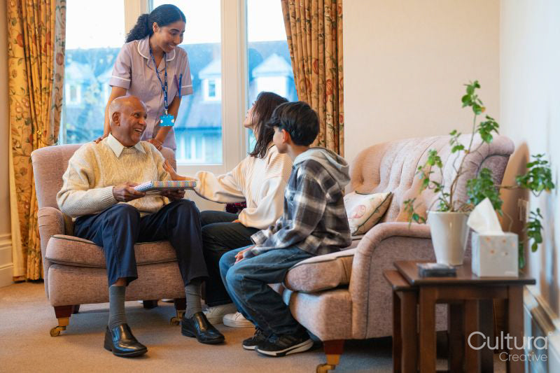 Adult daughter and grandson talking to care giver during visiting senior man in nursing home