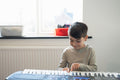 Boy playing music keyboard at home