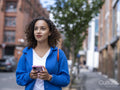 Smiling woman holding smart phone on street