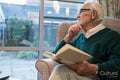 Senior man sitting in armchair and reading book