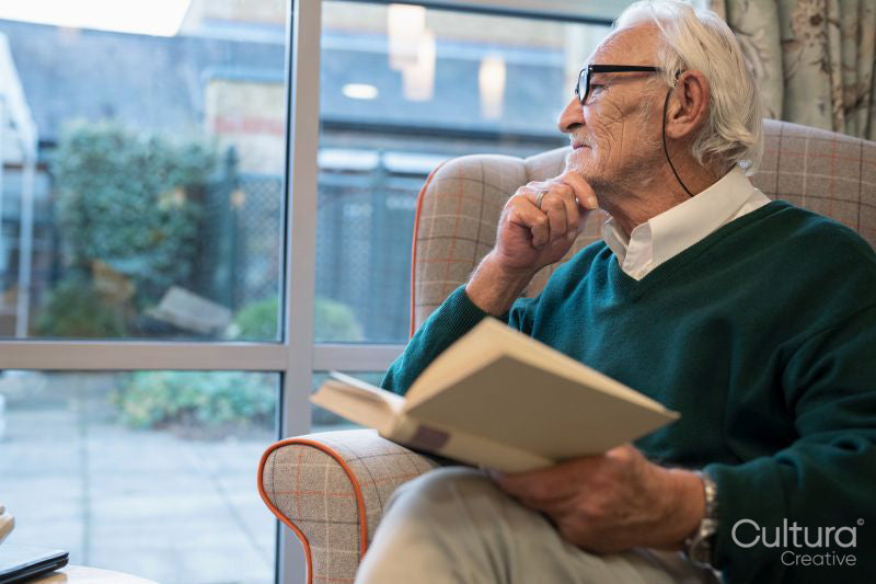 Senior man sitting in armchair and reading book