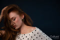Woman in polka dot top posing with hand on head
