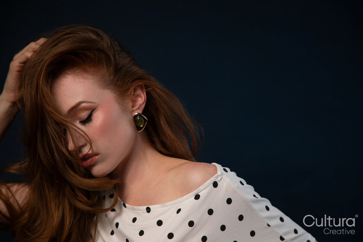 Woman in polka dot top posing with hand on head
