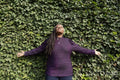 Portrait of beautiful woman with dreadlocks in front of ivy wall