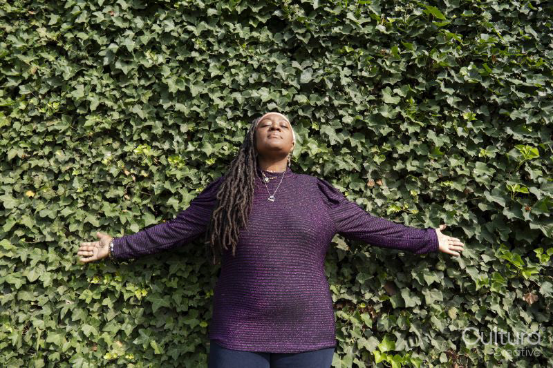 Portrait of beautiful woman with dreadlocks in front of ivy wall