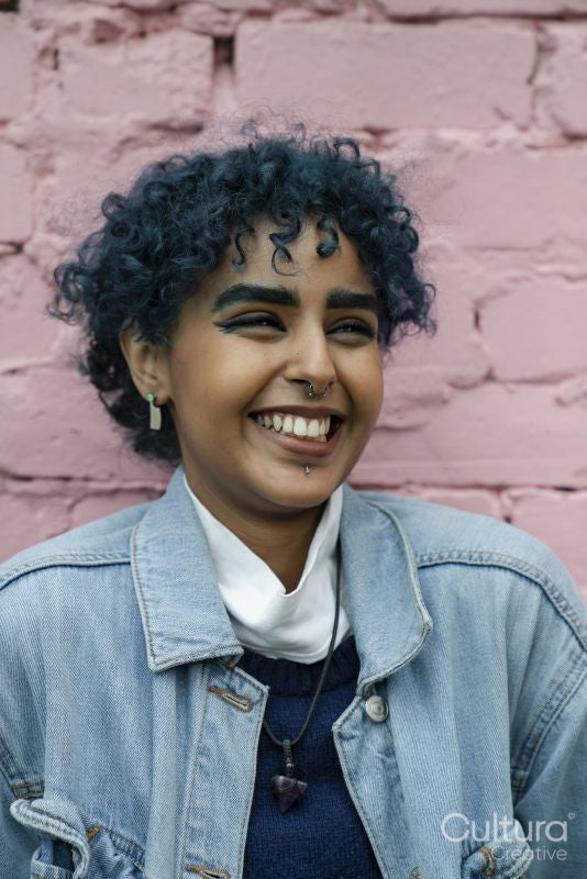 Smiling young woman standing against pink wall