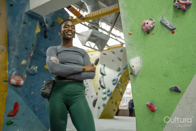 Portrait of smiling athletic woman at climbing wall at gym