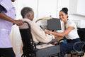Smiling female doctor talking to senior woman sitting in wheelchair in doctors office
