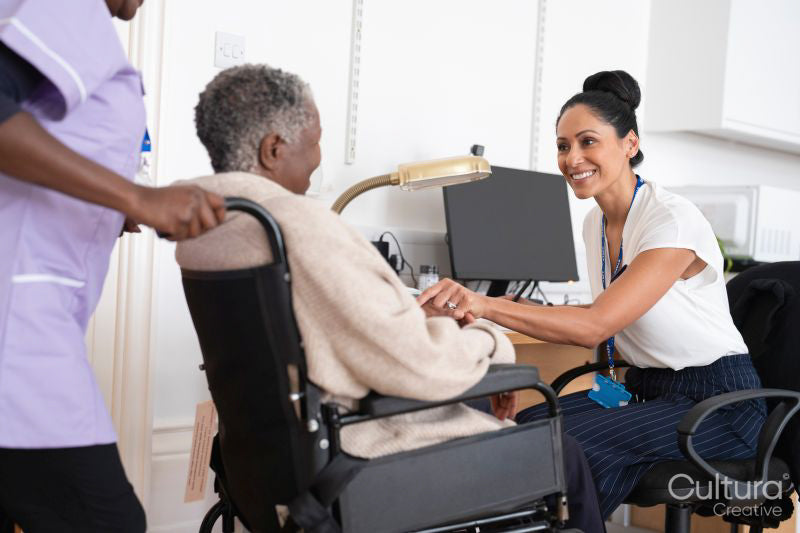 Smiling female doctor talking to senior woman sitting in wheelchair in doctors office