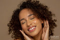 Close-up of smiling woman with curly hair and eyes closed