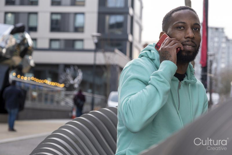 South Yorkshire, Man in green hooded shirt talking on phone in city