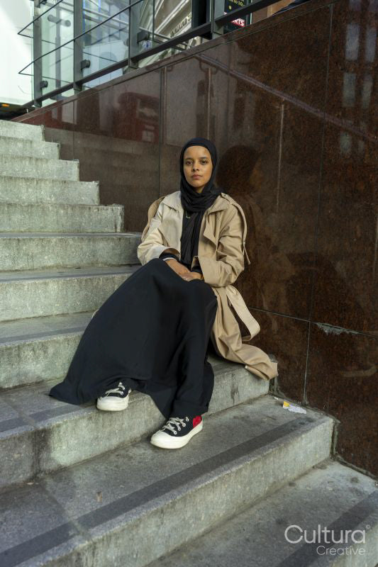 Young woman wearing hijab sitting outside office building