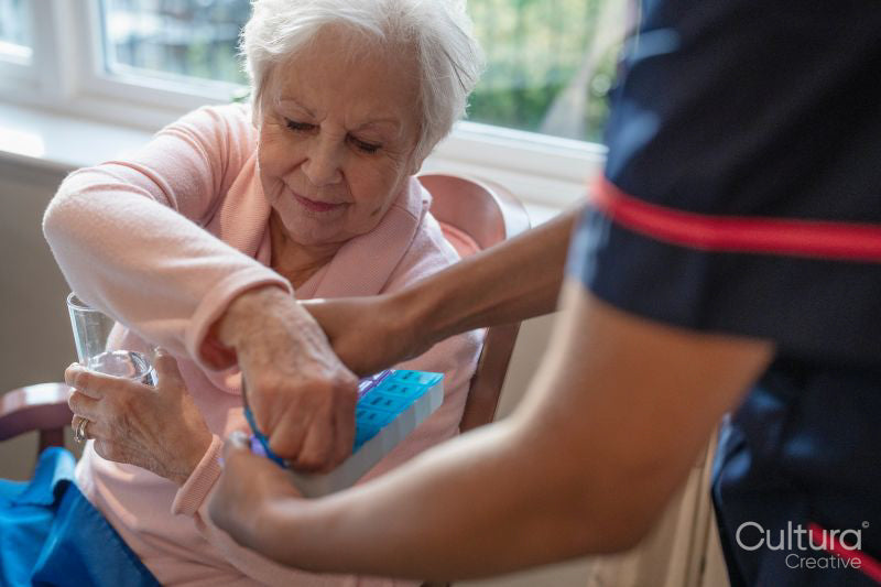 Nurse giving pill to senior lady in nursing home