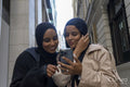 Two young women in city, looking at phone