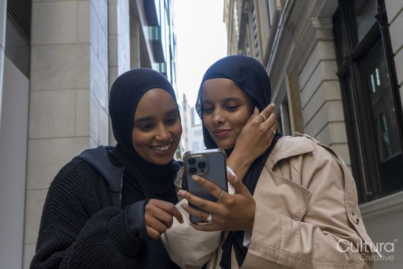 Two young women in city, looking at phone