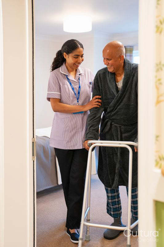Nurse helping senior man to walk with mobility walker at nursing home